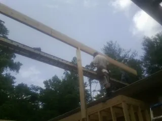Carpenter setting a ridge beam over a new addition frame — Ice Dam Removal by Roofing Brothers in Flinton