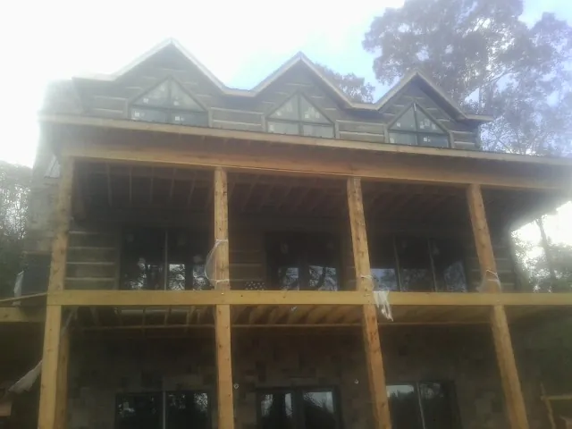 Dormers and porch framing on a large log home under construction — Roof Coating work by our crew in Flinton