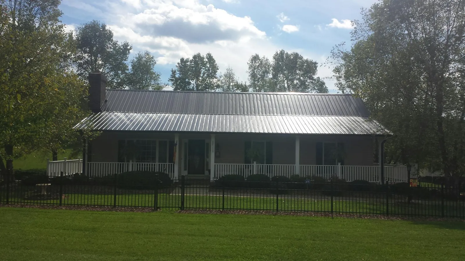 Gray metal roof on a brick ranch with a full width front porch — Gutter Guard Installation work by our crew in Flinton