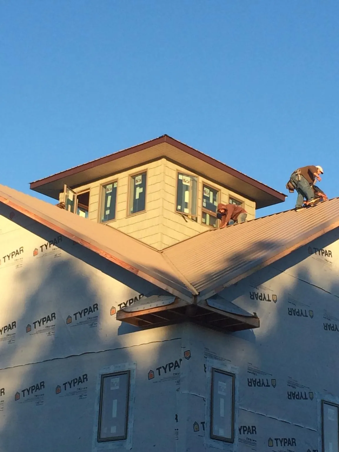 Roofers working around a rooftop cupola on a new metal roof at sunset — Roof Waterproofing in Flinton by Roofing Brothers